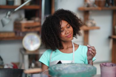 Çömlek atölyesindeki genç Afro kız, işyeri sahibi.