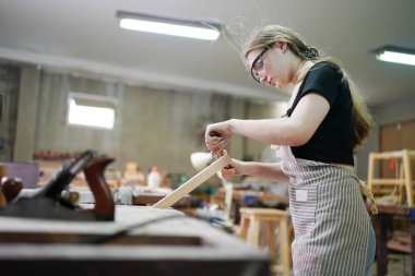 Genç bir kadının küçük işleri. Mobilya atölyesinde ahşabı ölçen genç ve güzel bir kadın işçi..