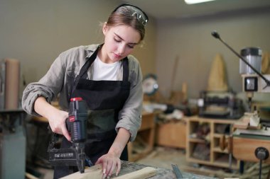 Marangoz DIY atölyesinde çalışan genç ve güzel bir kadın. Küçük işletme sahibi, mobilya fabrikasında çalışan genç bir kadın..