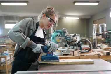 Marangoz DIY atölyesinde çalışan genç ve güzel bir kadın. Küçük işletme sahibi, mobilya fabrikasında çalışan genç bir kadın..