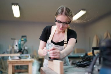 Marangoz DIY atölyesinde çalışan genç ve güzel bir kadın. Küçük işletme sahibi, mobilya fabrikasında çalışan genç bir kadın..