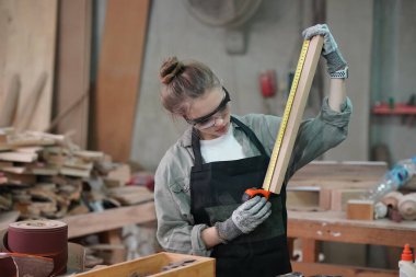 Genç bir kadının küçük işleri. Mobilya atölyesinde çalışan güzel genç bayan.