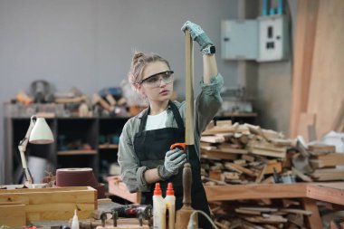 Genç bir kadının küçük işleri. Mobilya atölyesinde çalışan güzel genç bayan.