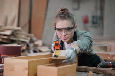 Genç bir kadının küçük işleri. Mobilya atölyesinde çalışan güzel genç bayan.