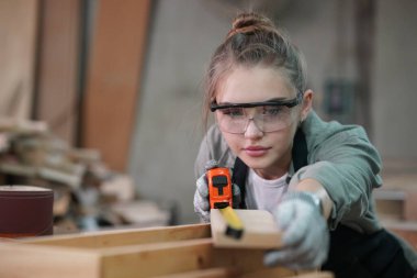 Marangoz DIY atölyesinde çalışan genç ve güzel bir kadın. Küçük işletme sahibi, mobilya fabrikasında çalışan genç bir kadın..