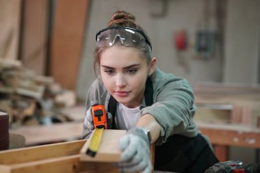 Genç bir kadının küçük işleri. Mobilya atölyesinde çalışan güzel genç bayan.