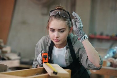 Genç bir kadının küçük işleri. Mobilya atölyesinde çalışan güzel genç bayan.