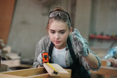 Genç bir kadının küçük işleri. Mobilya atölyesinde çalışan güzel genç bayan.