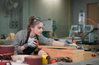 Marangoz DIY atölyesinde çalışan genç ve güzel bir kadın. Küçük işletme sahibi, mobilya fabrikasında çalışan genç bir kadın..