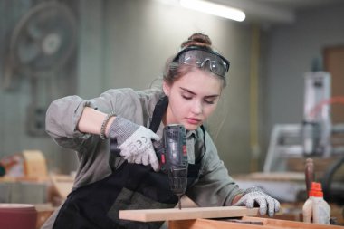 Marangoz DIY atölyesinde çalışan genç ve güzel bir kadın. Küçük işletme sahibi, mobilya fabrikasında çalışan genç bir kadın..