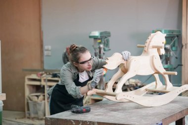 Genç bir kadının küçük işleri. Mobilya atölyesinde çalışan güzel genç bayan.