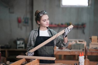 Marangoz DIY atölyesinde çalışan genç ve güzel bir kadın. Küçük işletme sahibi, mobilya fabrikasında çalışan genç bir kadın..