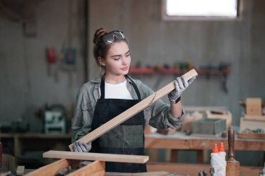 Genç bir kadının küçük işleri. Mobilya atölyesinde çalışan güzel genç bayan.