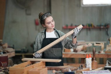 Marangoz DIY atölyesinde çalışan genç ve güzel bir kadın. Küçük işletme sahibi, mobilya fabrikasında çalışan genç bir kadın..