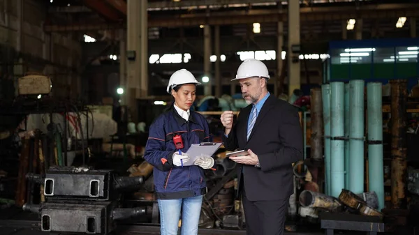 Factory manager or businessman and female engineer in factory. elegant man inspecting factory in industry plant background.