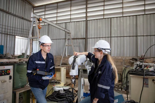 stock image Robotics engineers working on maintenance of modern robotic arm in factory warehouse 