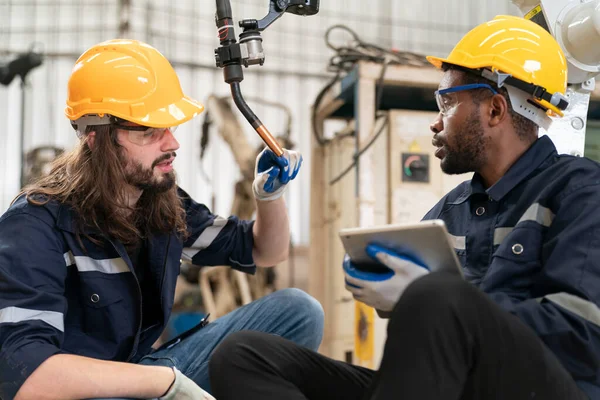 Robot mühendisi fabrika deposunda modern robotik kolun bakımı üzerinde çalışıyor.