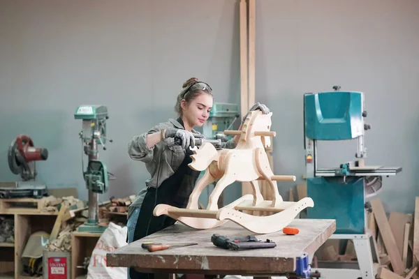 Genç bir kadının küçük işleri. Mobilya atölyesinde çalışan güzel genç bayan.