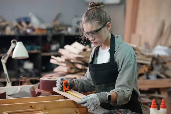 Genç bir kadının küçük işleri. Mobilya atölyesinde çalışan güzel genç bayan.
