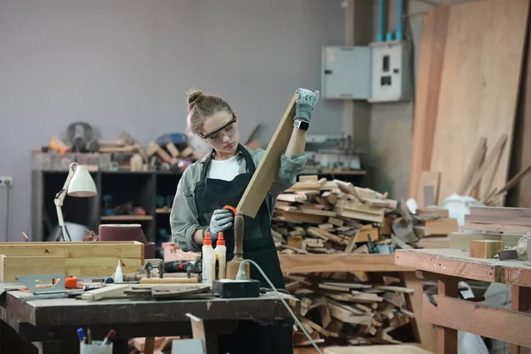 Genç bir kadının küçük işleri. Mobilya atölyesinde çalışan güzel genç bayan.