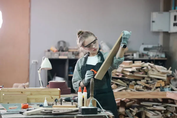 Genç bir kadının küçük işleri. Mobilya atölyesinde çalışan güzel genç bayan.