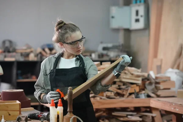 Genç bir kadının küçük işleri. Mobilya atölyesinde çalışan güzel genç bayan.