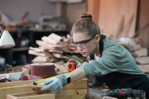 Genç bir kadının küçük işleri. Mobilya atölyesinde çalışan güzel genç bayan.