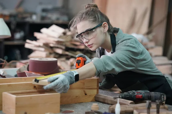 Genç bir kadının küçük işleri. Mobilya atölyesinde çalışan güzel genç bayan.