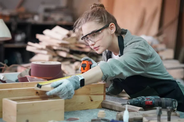Marangoz DIY atölyesinde çalışan genç ve güzel bir kadın. Küçük işletme sahibi, mobilya fabrikasında çalışan genç bir kadın..