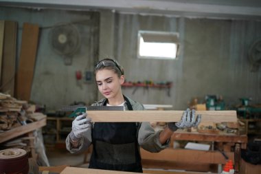 Genç bir kadının küçük işleri. Mobilya atölyesinde çalışan güzel genç bayan.