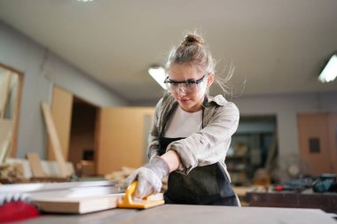 Marangoz DIY atölyesinde çalışan genç ve güzel bir kadın. Küçük işletme sahibi, mobilya fabrikasında çalışan genç bir kadın..