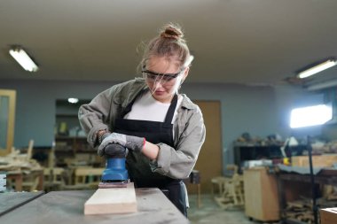 Genç bir kadının küçük işleri. Mobilya atölyesinde çalışan güzel genç bayan.