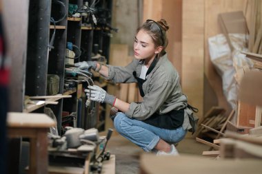 Genç bir kadının küçük işleri. Mobilya atölyesinde çalışan güzel genç bayan.