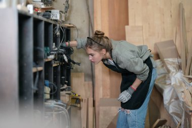 Genç bir kadının küçük işleri. Mobilya atölyesinde çalışan güzel genç bayan.