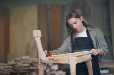 Genç bir kadının küçük işleri. Mobilya atölyesinde çalışan güzel genç bayan.