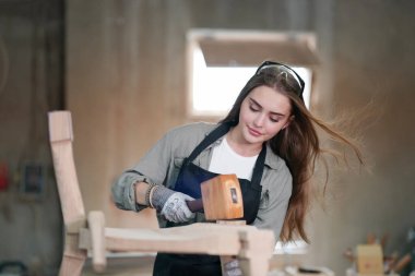 Marangoz DIY atölyesinde çalışan genç ve güzel bir kadın. Küçük işletme sahibi, mobilya fabrikasında çalışan genç bir kadın..
