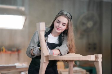 Marangoz DIY atölyesinde çalışan genç ve güzel bir kadın. Küçük işletme sahibi, mobilya fabrikasında çalışan genç bir kadın..