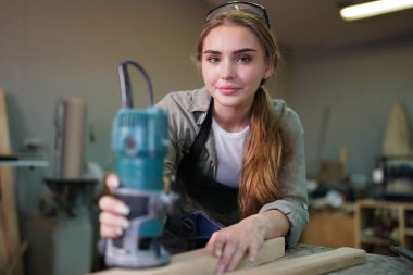 Genç bir kadının küçük işleri. Mobilya atölyesinde çalışan güzel genç bayan.