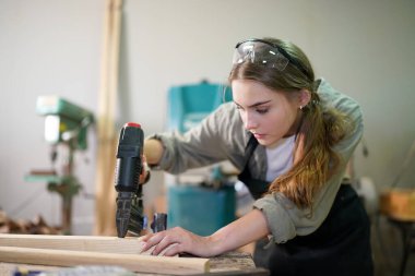 Genç bir kadının küçük işleri. Mobilya atölyesinde çalışan güzel genç bayan.