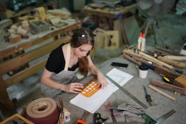 Small business of a young woman. Beautiful young woman worker in a furniture workroom clipart