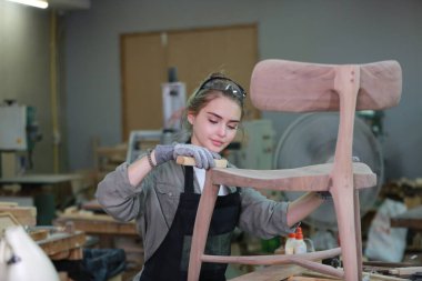 Genç bir kadının küçük işleri. Mobilya atölyesinde çalışan güzel genç bayan.