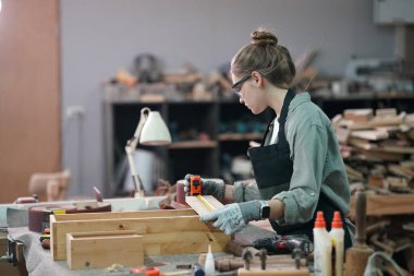 Genç bir kadının küçük işleri. Mobilya atölyesinde çalışan güzel genç bayan.