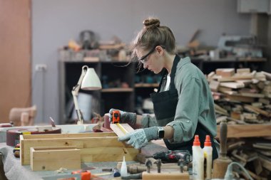 Genç bir kadının küçük işleri. Mobilya atölyesinde çalışan güzel genç bayan.