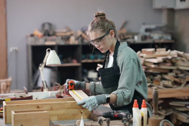 Genç bir kadının küçük işleri. Mobilya atölyesinde çalışan güzel genç bayan.