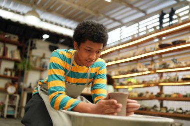 Genç Afro ergen el çömlekçisi çömlek atölyesinde kilden vazo yapıyor.