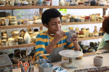 Genç Afro ergen el çömlekçisi çömlek atölyesinde kilden vazo yapıyor.