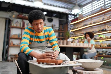 Genç Afro ergen el çömlekçisi çömlek atölyesinde kilden vazo yapıyor.