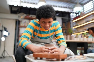 Genç Afro ergen el çömlekçisi çömlek atölyesinde kilden vazo yapıyor.
