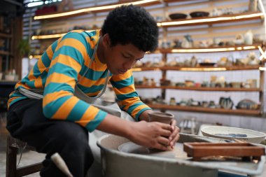 Genç Afro ergen el çömlekçisi çömlek atölyesinde kilden vazo yapıyor.