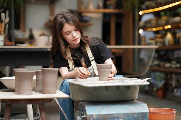 土船を形成しながら 陶器の車輪に座って 工芸品を使用してエプロンに集中した美しい職人のクローズアップ — ストック写真